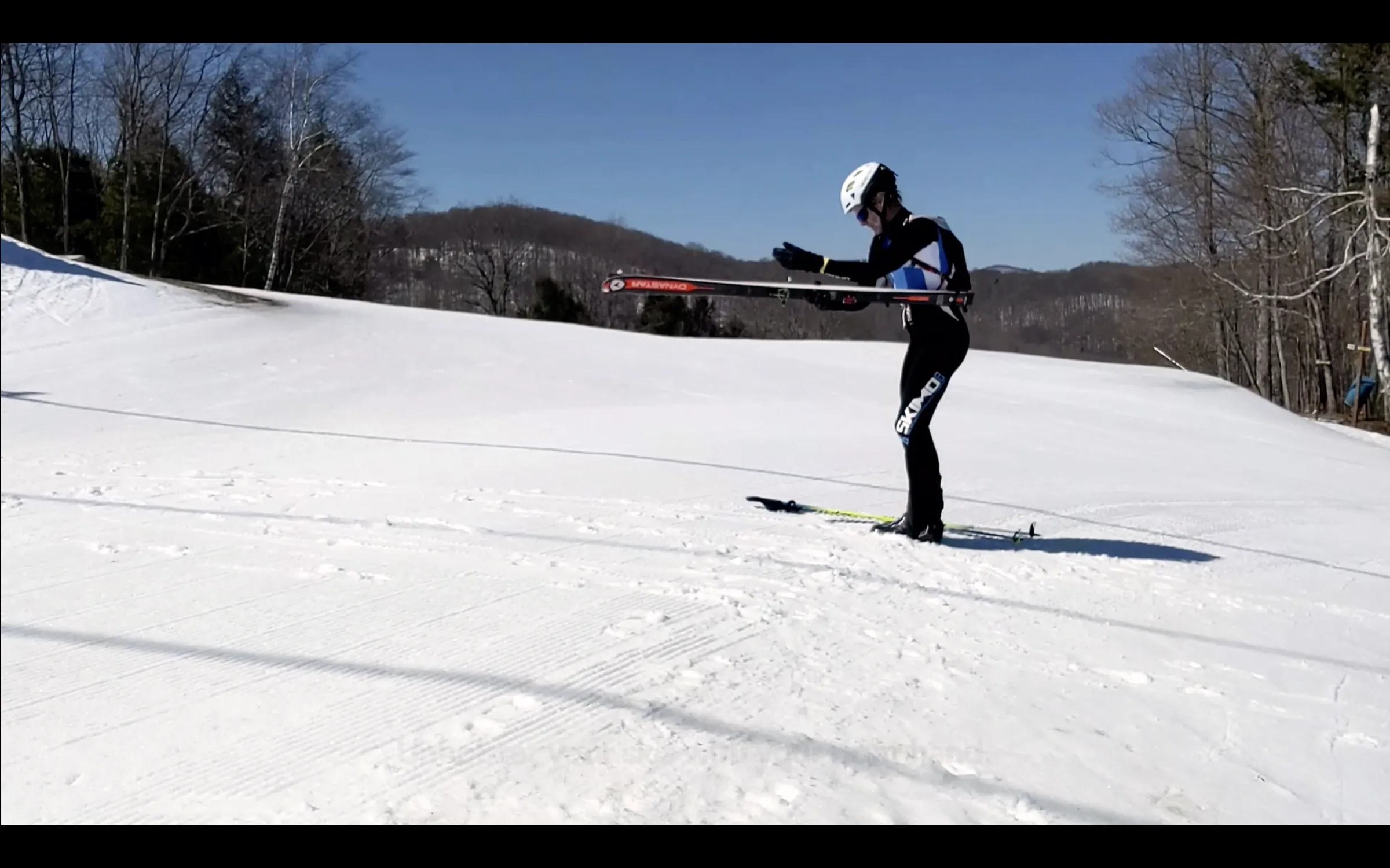 A photo of a skimo racer entering a boot-to-skin transition, removing skis from their holster