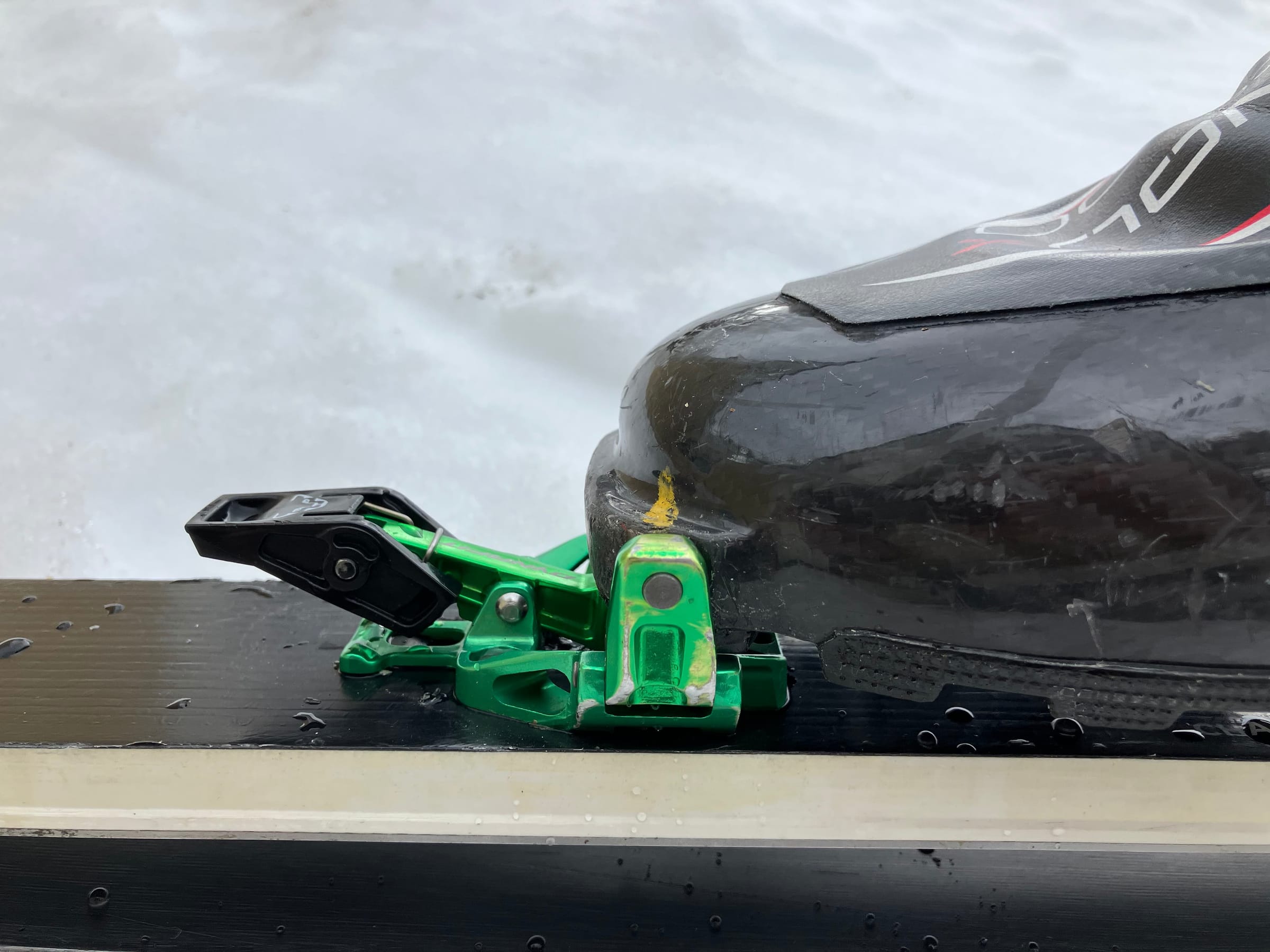 A side-view photo of the toe of a skimo boot in a binding with paint marks near the binding inserts.